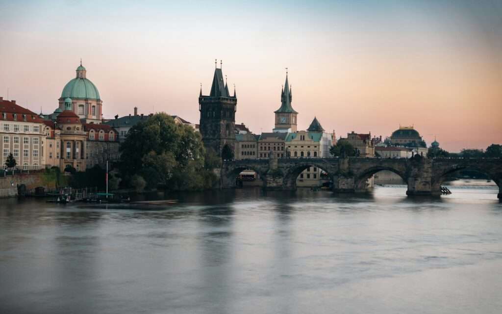 Charles Bridge and the Old Town bridge tower over a calm Vltava at dawn